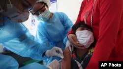 FILE -A young boy reacts as he receives a shot of the Sinovac's COVID-19 vaccine at a Samrong Krom health center outside Phnom Penh, Cambodia, Friday, Sept. 17, 2021. (AP Photo/Heng Sinith)