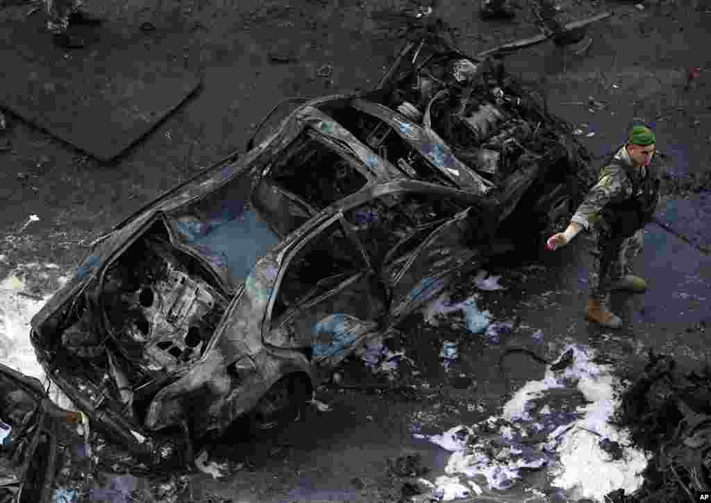 Um soldado do Exército Libanês parado junto a um carro destruído no local da explosão, na Baixa de Beirute, Líbano, Dez. 27, 2013. 