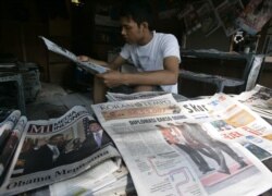 Penjaja koran membaca koran sambil menunggu pelanggan di Jakarta, 10 November 2010. (Foto: AP)