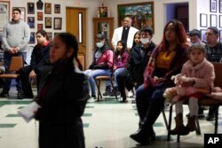 The Rev. Athanasius Abanulo stands behind a group of parishioners as they hold a special ceremony for the Lady of Guadalupe at Holy Family Catholic Church in Lanett, Ala., Dec. 12, 2021.