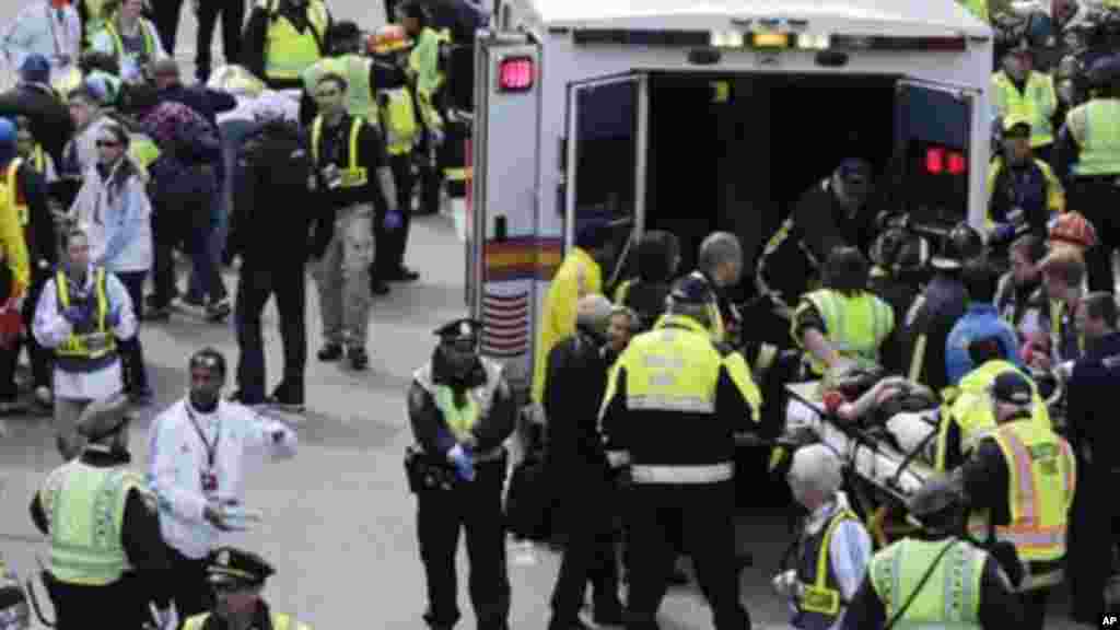 Param&eacute;dicos ajudam feridos junto &agrave; linha de chegada da Maratona de Boston 2013, ap&oacute;s as explos&otilde;es no dia 15 de Abril de 2013.