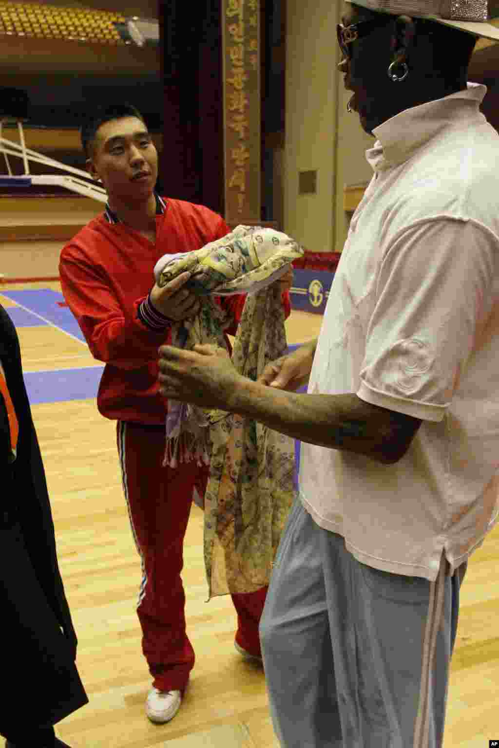 A North Korean basketball player returns the scarf that Dennis Rodman was wearing and took off during a practice with North Korean and U.S. basketball players in Pyongyang, Jan. 7, 2014. 