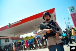 Seorang petugas kepolisian berjaga di depan SPBU Pertamina setelah gempa dan tsunami yang melanda Palu, Sulawesi Tengah, Senin, 1 Oktober 2018. (Foto:AP)