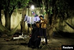 A Venezuelan man cuts the hair of his friend at a gym which has turned into a shelter for Venezuelans in Boa Vista, Brazil, Nov. 17, 2017.