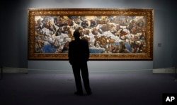 FILE - A man looks at "The Coronation of the Virgin, The Paradise" a painting by 16th century Venetian artist Tintoretto at the Thyssen-Bornemisza Museum in Madrid, June 7, 2006.