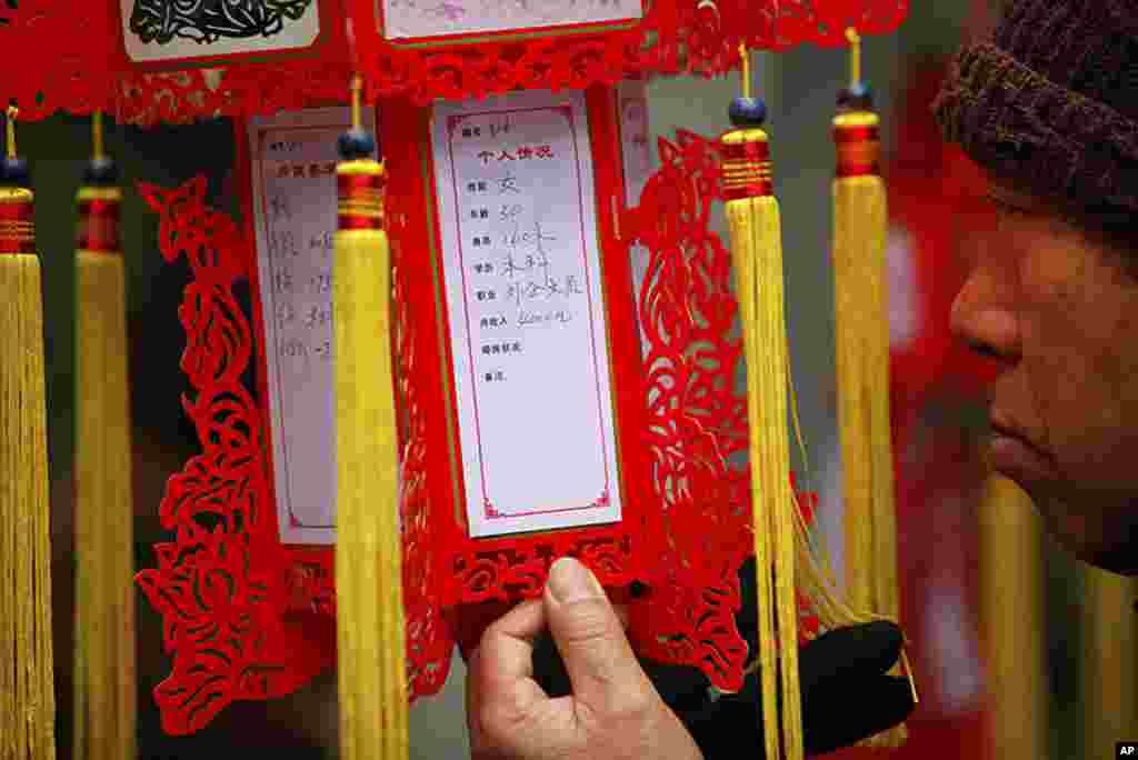 A parent looks at a red lantern with personal information displayed during a Valentine's Day event at the People's Park in Shanghai, February 14, 2012. The event is organized by the local government to help parents look for dating opportunities for their 