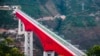 In this photo released by Xinhua News Agency, an electric multiple unit (EMU) train of the China-Laos Railway crosses a major bridge over the Yuanjiang River in southwestern China's Yunnan Province, Dec. 3, 2021. 