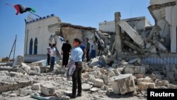 People inspect the damage done to a Sufi shrine, the tomb of Sidi Mohamed Landoulsi, after an explosion in the Tajoura neighborhood on the outskirts of Tripoli, March 28, 2013. 