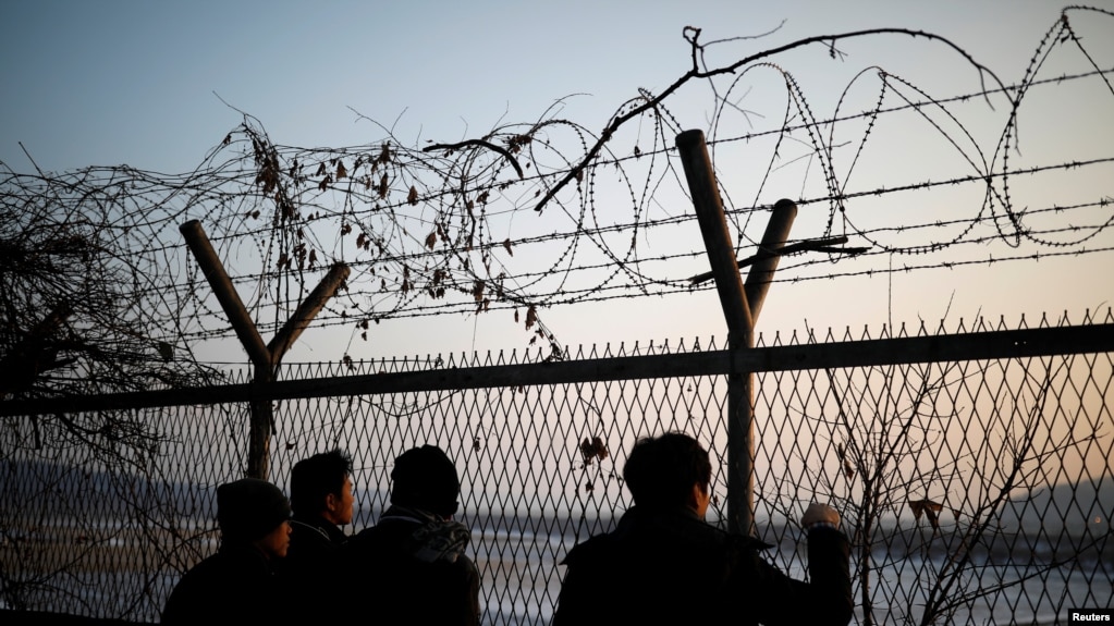 People look toward the north through a barbed-wire fence near the militarized zone separating the two Koreas, in Paju, South Korea, Dec. 21, 2017.