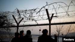 People look toward the north through a barbed-wire fence near the militarized zone separating the two Koreas, in Paju, South Korea, Dec. 21, 2017.