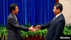 Japan's Prime Minister Shinzo Abe shakes hands with China's President Xi Jinping (R) during their meeting at the Great Hall of the People, on the sidelines of the Asia Pacific Economic Cooperation (APEC) meetings, in Beijing, Nov. 10, 2014. 