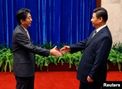 Japan's Prime Minister Shinzo Abe shakes hands with China's President Xi Jinping (R) during their meeting at the Great Hall of the People, in Beijing, Nov. 10, 2014.