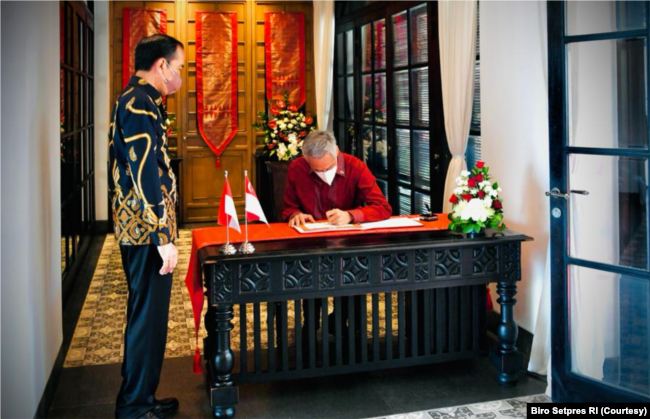 PM Singapura Lee Hsien Loong menulis di buku tamu disaksikan Presiden Jokowi. (Foto: Courtesy/Setpres RI)