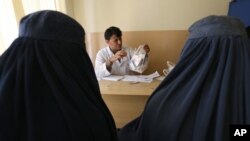 FILE - An Afghan mental health doctor, center, talks with patients in the Mental Health and Drug Addicts' Hospital in Kabul, Afghanistan, July 17, 2016.