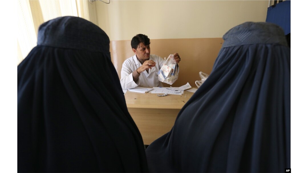 FILE - An Afghan mental health doctor, center, talks with patients in the Mental Health and Drug Addicts' Hospital in Kabul, Afghanistan, July 17, 2016.