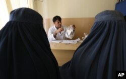 FILE - An Afghan mental health doctor, center, talks with patients in the Mental Health and Drug Addicts' Hospital in Kabul, Afghanistan, July 17, 2016.