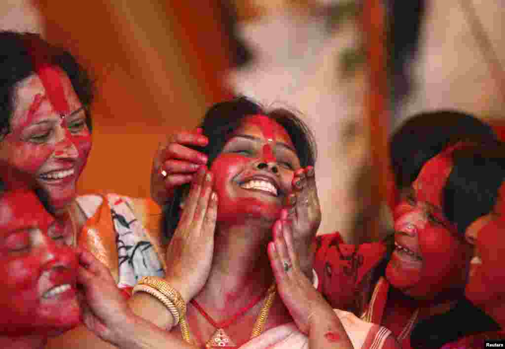 Hindu women apply &#39;Sindur&#39;, or vermillion powder, on the face of a woman during the Durga Puja festival in the northern Indian city of Chandigarh. 