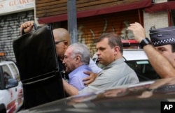 A bodyguard holds up a briefcase to shield Brazil's President Michel Temer as several people shout obscenities and throw objects at him, after Temer visited the area where a building caught fire and collapsed, in Sao Paulo, Brazil, May 1, 2018. "We will provide assistance to the victims of this disaster," said Temer, who has been charged with corruption and has approval ratings in the single digits.