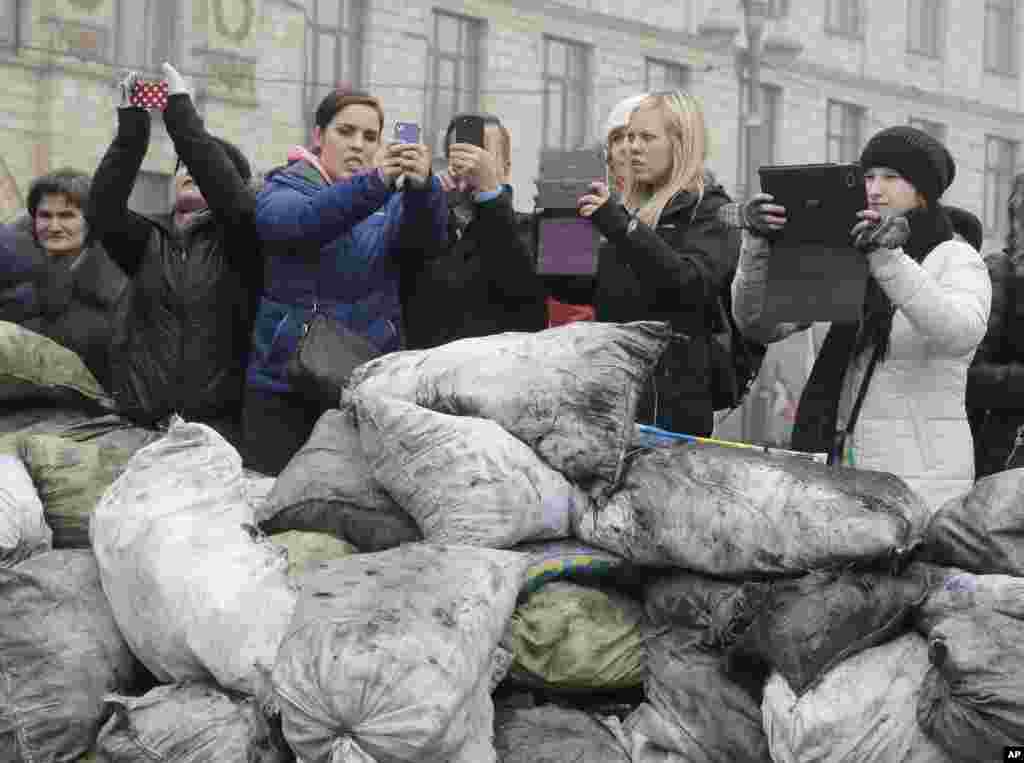 Tourists take photos of barricades in front of riot police in central Kyiv, Feb. 9, 2014. 