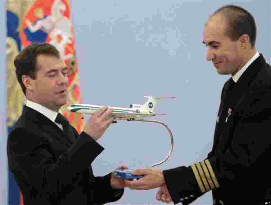 Russian President Dmitry Medvedev, left, is presented with a model of an Alrosa Tu-154 aircraft by aircraft captain Yevgeny Novoselov whom he awards with a medal during an award ceremony in the Gorki residence outside Moscow, Tuesday, Nov. 16, 2010. Medve