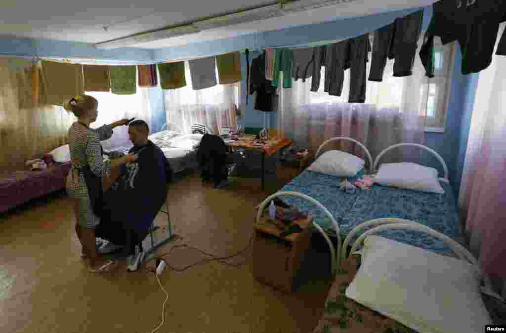 A woman shaves a man's head in their room at the "Zharki" health resort, outside the village of Rybnoye, Sept. 4, 2014.