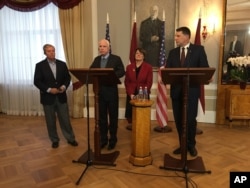 Latvian President Raimonds Vejonis, right, looks at US Sen. John McCain centre left, during a press conference, Wednesday, Dec. 28, 2016 in Riga, Latvia, while Lindsey Graham, and Amy Klobuchar stand in the background.