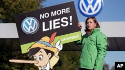 An activist with the environmental group Greenpeace protests Volkswagen emissions rigging. She stands outside a VW factory in Wolfsburg, Germany, Sept. 25, 2015.