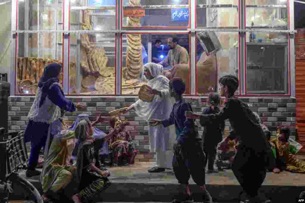 A woman gives bread to young people in need in front of bakery in Kabul, Afghanistan, Sept. 19, 2021.