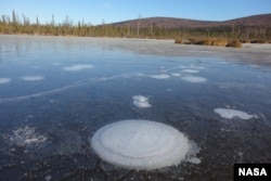 Methane bubbles up from the thawed permafrost at the bottom of the thermokarst lake through the ice at its surface. (Katey Walter Anthony/ University of Alaska Fairbanks)