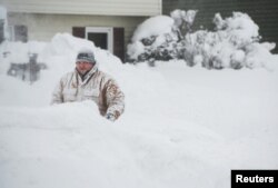 Thomas Berry removes snow from the sidewalk in front of his home after two days of record-breaking snowfall in Erie, Pennsylvania, Dec. 27, 2017.