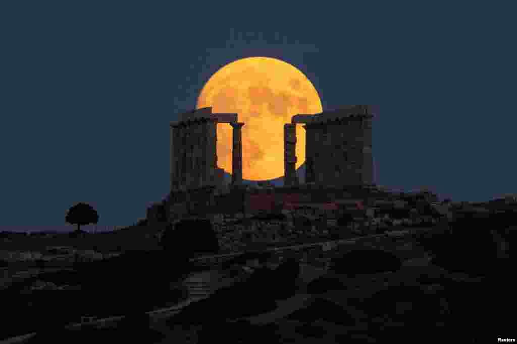 An almost full moon rises over the Temple of Poseidon in Cape Sounion, near Athens, Greece, Aug. 21, 2021.