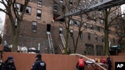 Bomberos y oficiales de la policía de Nueva York trabajan afuera de un edificio de apartamentos después de un incendio en el Bronx, en la ciudad de Nueva York, el 9 de enero de 2022.