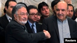 Afghan presidential candidate Qayum Karzai (R) shakes hand with fellow presidential candidate Zalmai Rassoul during a news conference in Kabul, March 6, 2014.