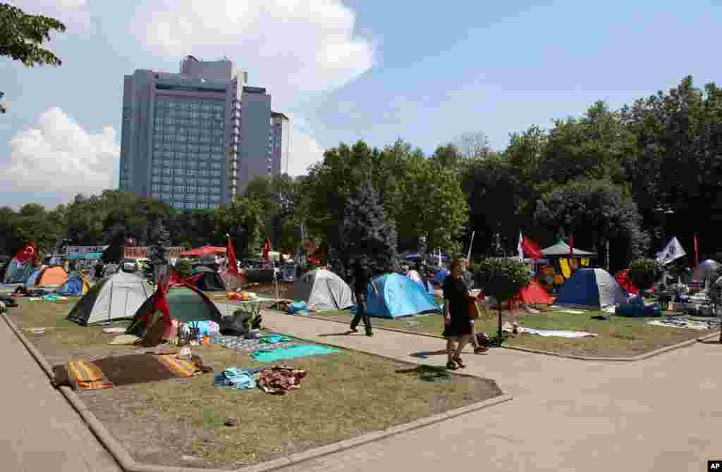 Pedestrians walk among tents set up by protesters in Gezi park, Taksim Square, Istanbul, June 6, 2013.