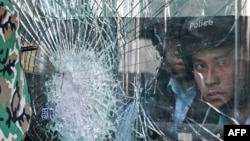 Cảnh sát đứng bên trong tòa nhà chính phủ bị người biểu tình đập cửa kính