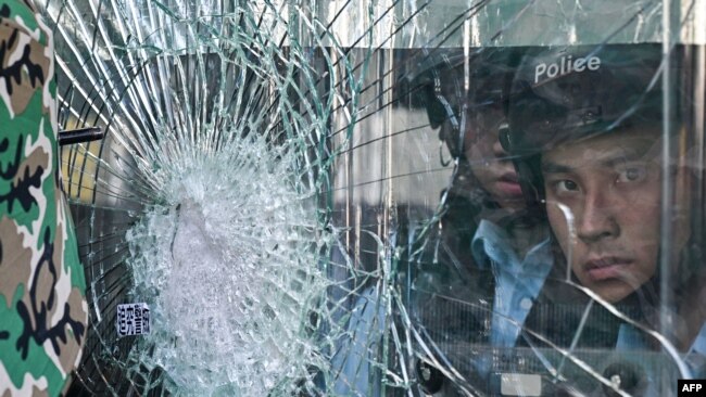 一名香港警察透过被砸裂的玻璃望向示威者