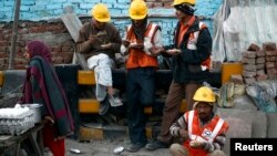 FILE - Laborers eat during a break from their work at the site of a commercial building under construction in Noida, on the outskirts of New Delhi, Dec. 13, 2013.