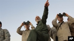 FILE - Photo by the government-controlled Syrian Central Military Media shows Iran's Army Chief of Staff Maj. Gen. Mohammad Bagheri, with binoculars, as he visits senior Iranian military officers in the northern province of Aleppo, Syria, Oct. 17, 2017. 