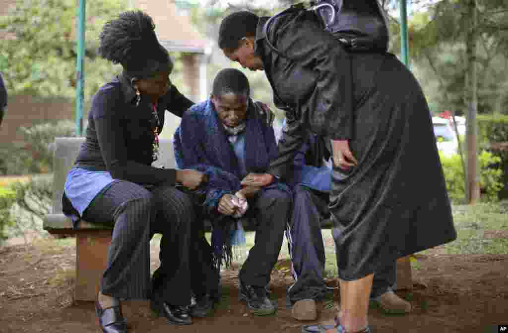 Des parents réconfortent Stephen (au c.) dont le père est mort dans l&#39;attaque de samedi contre le Westgate Mall, à Nairobi, Kenya, alors qu&#39;il attend le résultat de l&#39;autopsie à la morgue municipale, le 23 septembre 2013.