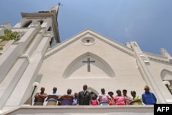 FILE - Members of the Emanuel African Methodist Church stand in front of the church and announce that services and Sunday school will go on as scheduled Sunday, four days after the pastor and eight others were slain in the church in Charleston, S.C., June 20, 2016.
