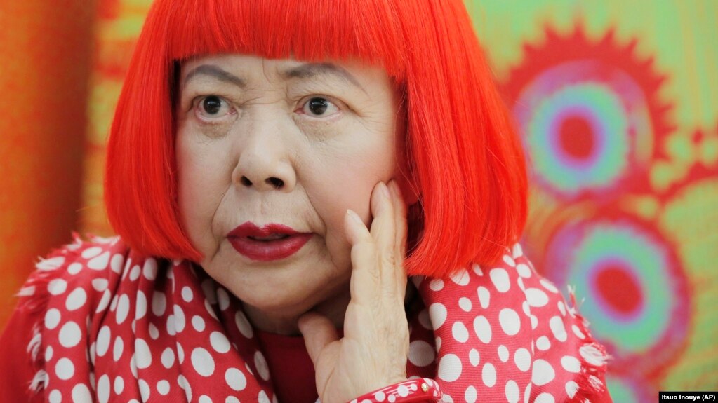 In this photo taken Wednesday, August 1, 2012, Japanese artist Yayoi Kusama wears a bright red wig and a Louis Vuitton polka dot scarf. Her art is known for its colorful use of dots. (AP Photo/Itsuo Inouye)