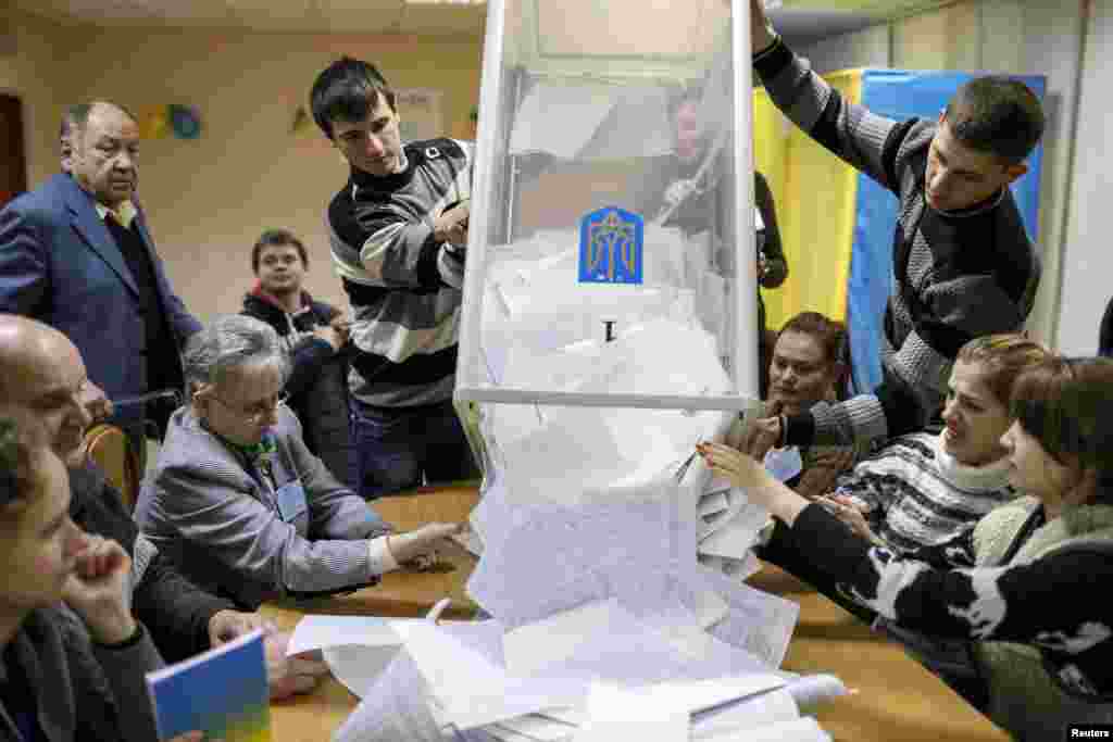 Members of a local election commission empty a ballot box at a polling station after voting in Kyiv, Oct. 26, 2014.