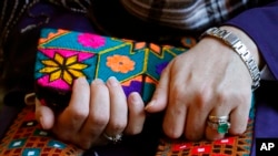 A Massachusetts resident identifying herself only as Safi, who asked that her last name not be used for fear of retribution against her relatives in Afghanistan, holds a purse with traditional Afghan patterns, Nov. 9, 2021.