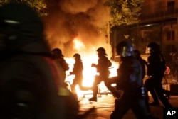 Police officers are silhouetted by fires lit by demonstrators during a protest against the G-20 summit in Hamburg, northern Germany, July 6, 2017.