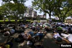 Children perform a die-in in front of the Atomic Bomb Dome in Hiroshima, western Japan, August 5, 2015. Japan will mark on Thursday the 70th anniversary of the attack on Hiroshima, where the U.S. dropped an atomic bomb on August 6, 1945.