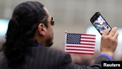 An immigrant takes a selfie photo before participating in a naturalization ceremony to become new U.S. citizens in Los Angeles, California, March 20, 2018. 