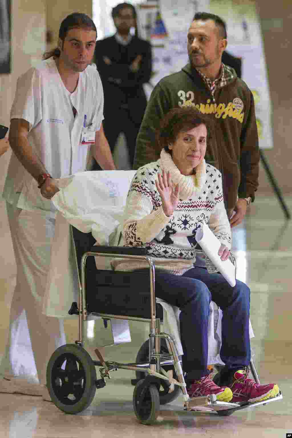 Avec à ses côtés son mari Javier Limon, Teresa Romero, infirmière auxiliaire espagnole, guérie du virus Ebola, assise sur un fauteuil roulant et poussé par un membre du personnel de santé, a été libéré d&#39;un hôpital de Madrid un mois après qu&rsquo;elle a été confirmée infectée par le virus. Elle est la première personne connue à avoir contracté la maladie en dehors de l&#39;Afrique de l&#39;Ouest dans la dernière flambée. (AP Photo / Andres Kudacki) 