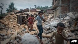 Anak-anak Nepal menutup hidung akibat bau jenazah korban gempa saat melewati puing-puing di Chautara, 80 kilometer dari ibukota Kathmandu (foto: dok). Nepal kembali diguncang gempa Selasa (12/5) sore. 