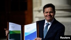 FILE - Ireland's Minister for Finance Paschal Donohoe displays a copy of the 2019 budget on the steps of Government Buildings in Dublin, Ireland, Oct. 9, 2018.