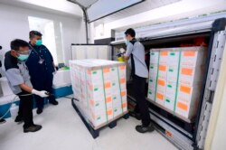 In this photo released by Indonesian Presidential Palace, workers spray disinfectant on boxes containing experimental coronavirus vaccines made by Chinese company Sinovac arriving at a facility of state-owned pharmaceutical company Bio Farma